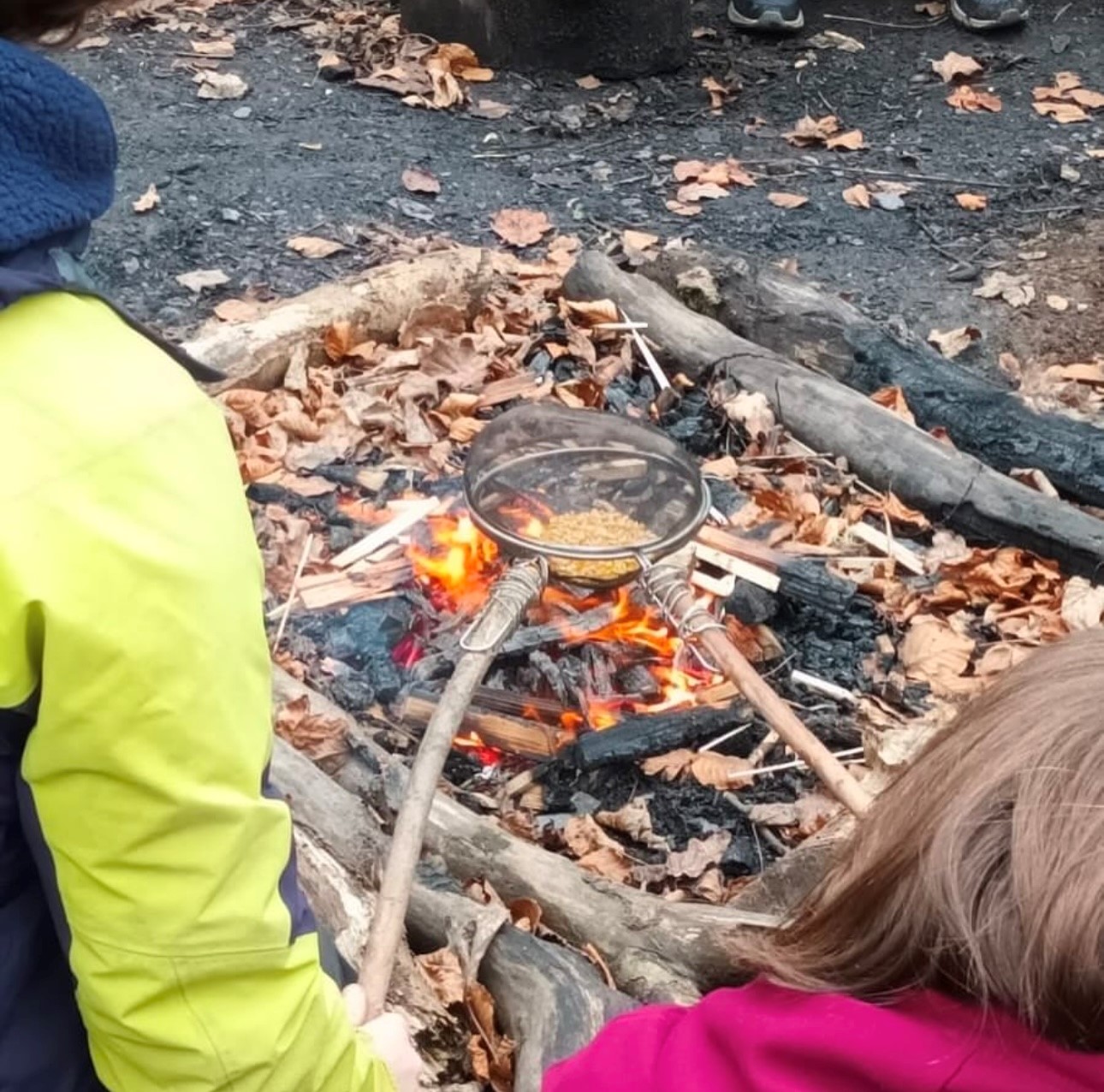 Students learning to warm up food on a campfire