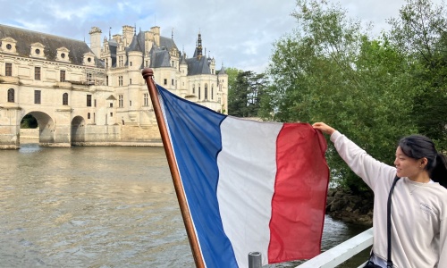 Student holding the French flag in front of Chenonceau castle
