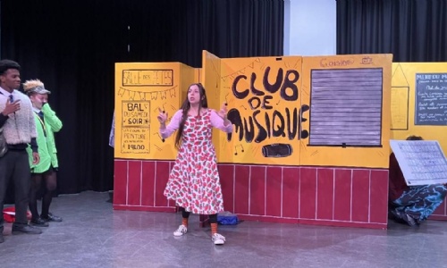 Two students performing on stage with French actress