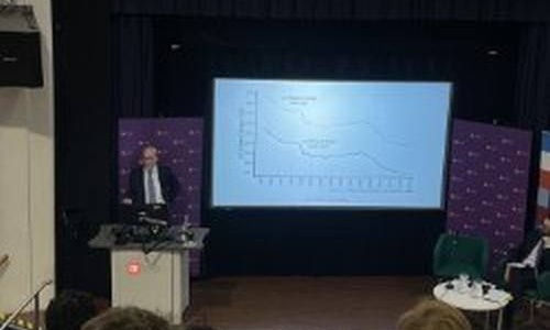 Speaker presenting slides in front of packed room